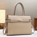 Detail of beige textured handbag with gold twist lock and leather stitching on white desk - Khaki