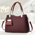 Close-up of burgundy handbag with textured finish, silver hardware, and mini charm - Burgundy