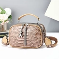 Nahaufnahme der khakifarbenen Kroko-Optik Tasche mit Bärenanhänger und Quasten-Details - Kurkuma
