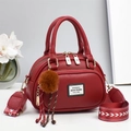 Detail of wine red pebble leather handbag with wide arrow strap and plush charm - Burgundy