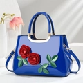 Detail of bright blue patent leather handbag with 3D red roses and gold metal handle - Blue