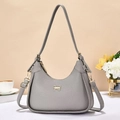 Grey vintage half-moon shoulder bag with golden bow detail on a minimalist table - Gray
