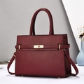 Detail of burgundy pebble leather handbag featuring golden twist lock and sturdy handles - Wine Red