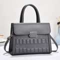Close-up of dark grey crossbody bag featuring embossed texture and gold buckle - Gray