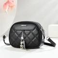 Close-up of black quilted crossbody bag with silver hardware and bear charm detail - Black