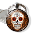 Detailliertes Makro eines Sugar-Skull Glascabochon-Anhängers an einem Metallschlüsselring - Star Eye Reben-Schädel-Design (JY004107-7)