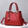 Dettaglio della borsa in pelle rossa con cuciture curve e ciondolo a forma di ciliegia - Borgogna