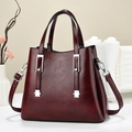 Detail der weinroten Shopper-Tasche mit Glanzeffekt und silbernen Metallschnallen im Dekor - Weinrot