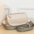 Detail of cream crossbody bag with wide woven strap and gold hardware on woven mat - Khaki