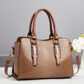 Detailed macro view of the brown crocodile pattern texture and golden metal hardware - Brown
