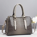 Close-up of crocodile embossed texture on a taupe tote bag with golden hardware - Gray