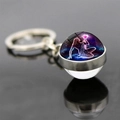 Macro shot of glass ball keychain with Aquarius zodiac goddess on a reflective surface - Aquarius