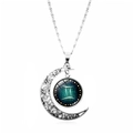 Macro detail of silver moon pendant with Gemini zodiac constellation glass dome - Gemini