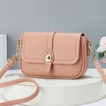 Pink lychee texture leather crossbody bag with gold twist lock on white display stand - Pink