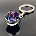 Close-up of double-sided glass ball keychain with glowing purple Aquarius zodiac theme - Aquarius