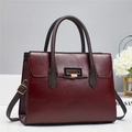 Close-up of deep red leather tote bag featuring gold buckle and brown handles - 29x12x22cm / Red