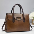 Detail view of brown leather tote bag with gold rectangular lock and floral decor - 29x12x22cm / Coffee