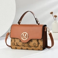 Detalle de bolso de cuero marrón con hebilla M dorada y elegante diseño floral - Amarillo Tierra
