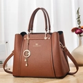 Détail d'un sac à main marron foncé en cuir grainé avec logo kangourou doré et pendentif étoile - Jaune Terre
