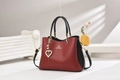 Détail du sac en cuir rouge et noir avec logo doré et breloque perle en cœur - Noir avec Rouge