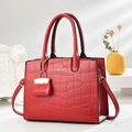 Sac à main rouge texture crocodile avec pendentif et doubles poignées sur fond minimaliste - Bordeaux