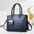 Détail du sac à main bleu marine en cuir croco avec mini charm et embossage doré élégant - Bleu