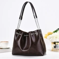 Dettaglio della borsa tote in pelle PU marrone scuro con catena argento in un caffè accogliente - caffè