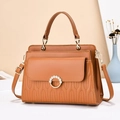 Detail of tan caramel handbag showing wavy quilted patterns and pearl ring closure - Length 27cm Width 10cm Height 18cm / Earthy Yellow
