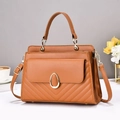 Detail of a brown leather handbag with V-shaped quilting and a gold oval buckle clasp - Earthy Yellow