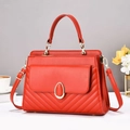 Detail of red leather handbag with V-shaped quilting and gold oval twist lock closure - Red