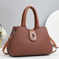 Detail of a brown woven texture handbag featuring a silver teardrop twist lock closure - L32 W14 H22 / Earthy Yellow