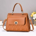Close-up of caramel leather handbag with heart quilting and elegant metal buckle - Earthy Yellow