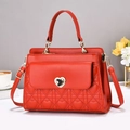 Detailed view of red quilted handbag featuring a gold heart-shaped metal twist lock closure - Red