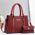 Detail view of burgundy tote bag set with textured vertical patterns and gold hardware - Red