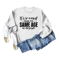 Flat lay of white sweatshirt featuring It's so weird slogan with denim and sneakers - S / White (Black Font)