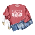Close-up of red crewneck sweatshirt with white 'It's so weird' text flat lay display - S / Red (White Font)