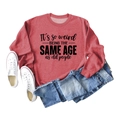 Red crewneck sweatshirt with 'It's so weird' slogan print and flat lay clothing display - S / Red (Black Font)