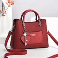 Detail of red embossed leather handbag featuring silver hardware and heart charm - Burgundy
