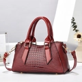 Close-up of burgundy crocodile pattern handbag with glossy details and golden hardware - Wine Red