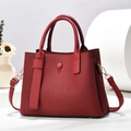 Détail d'un sac à bandoulière rouge plissé avec finitions dorées sur socle épuré - L26xl10xH19cm / Bordeaux