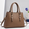 Détail du sac à main en cuir grainé marron foncé avec rivets dorés et bandoulière - café