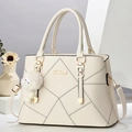 Modische gesteppte Makronen-Umhängetasche in Beige mit Pompon und Logo - Gebrochenes Weiß