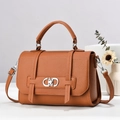 Detail of silver oval metal lock on caramel litchi grain leather handbag with top handle - Earthy Yellow