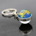 Gros plan d'un porte-clés globe terrestre en métal argenté avec carte du monde sur fond sombre - Terre Géographique en Couleur (JY006262-18)