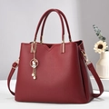 Close-up of wine red lychee pattern handbag with golden rabbit pearl charm detail - Burgundy