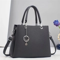 Detail of dark grey striped handbag featuring dual handles and silver smiley face charm - Gray