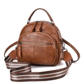 Detail of brown litchi grain leather backpack featuring a colorful striped woven strap - Khaki