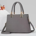 Graue Handtasche mit gewebter Textur, Trapezform, runden Griffen und goldenen Beschlägen - Schwarz