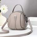 Detailed view of taupe lychee leather round bag with silver U-shaped metal hardware - Light Gray