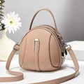 Detail van ronde beige crossbodytas met dubbele ritssluiting en leertextuur - Abrikoos